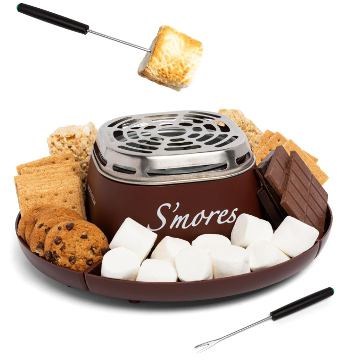 Brown tabletop s’mores maker shown with roasting forks, marshmallows, chocolate and crackers.